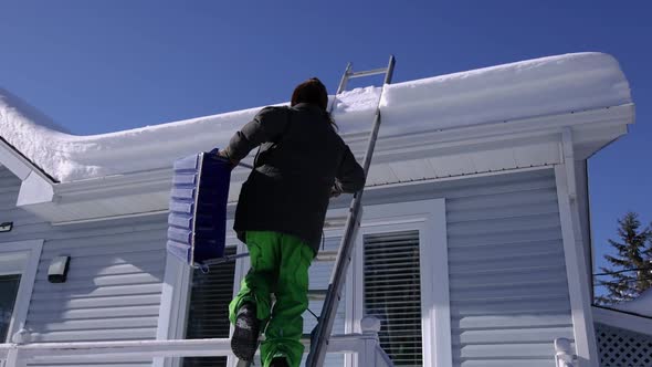 Removing Fresh Snow From a Roof in a Sunny Winter Day