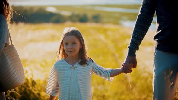 Little Girl Walking on the Wheat Field and Holding Hand of Her Father