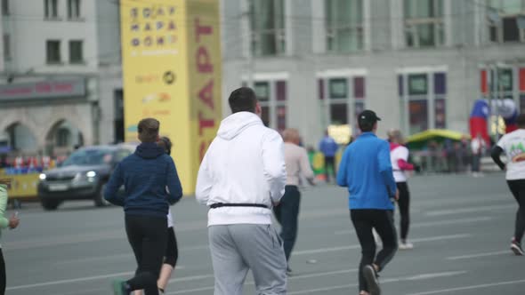 Back Rear View on Big Chunky Sportsman Running Among Crowd of Marathon Athletes