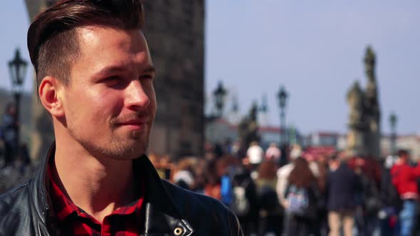 A Young Handsome Man Takes Photos on a Town Square - Face Closeup - People in the Blurry Background