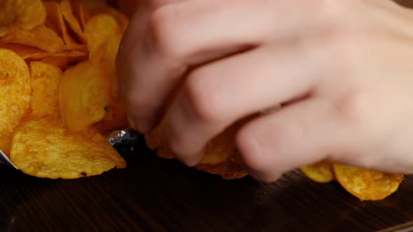 Hand Takes Golden Potato Chips From the Pack