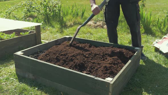 Leveling compost with shovel in raised garden bed