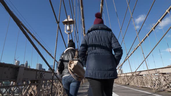 Two Girls Walk Over the Famous Brooklyn Bridge in New York
