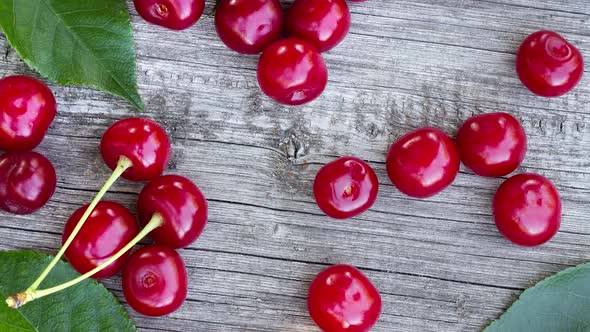 Ripe Juicy Red Cherry with Green Leaves Lies on Old Cracked Wooden Table As Summer Natural