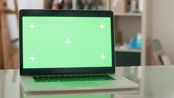 Laptop with Green Screen on a Glass Office Desk