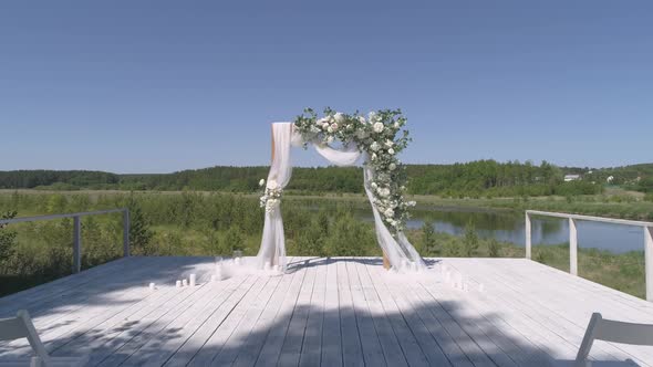 Drone view of wedding arch on the pier by the river next to the forest 33