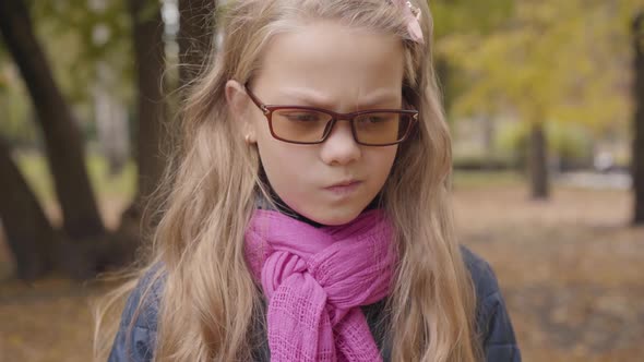 Portrait of an Angry Caucasian Teenage Girl Standing in the Autumn Park and Looking at the Camera