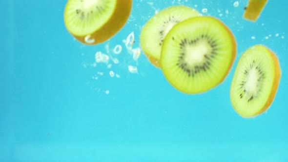 slices of kiwi fruit splash into water in slow motion