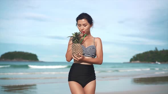 Girl Drinking Cocktail in Pineapple on the Beach