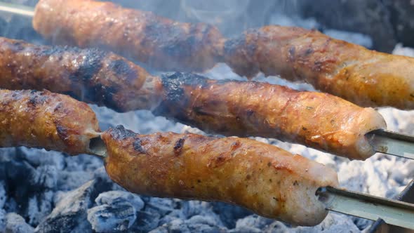 Sausages on Skewers are Cooked on the Portable Grill Outdoor Close Up BBQ