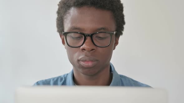 Close Up of Young African Man Looking at Camera While Using Laptop in Office