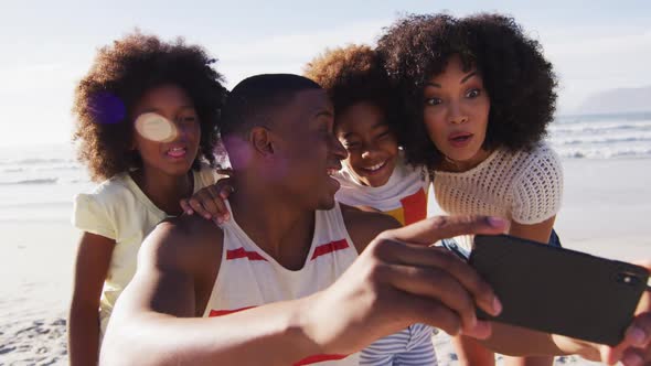 African american parents and their children taking a selfie with smartphone on the beach