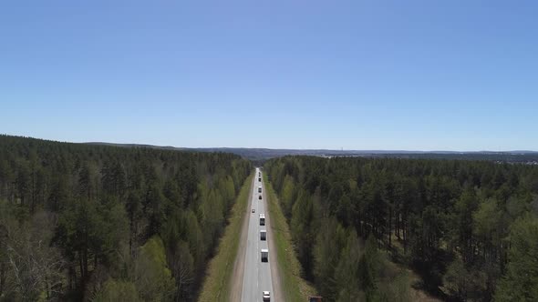 Aerial view of cars go on the highway, the highway goes through the forest 02