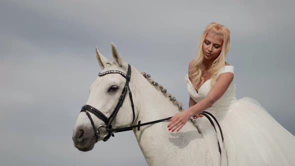 Portrait of a Blonde in a White Dress Sitting on a Horse