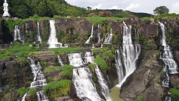 Cinematic Aerial of Scenic Waterfall in Asia in Tropical Jungle with Lady Buddha