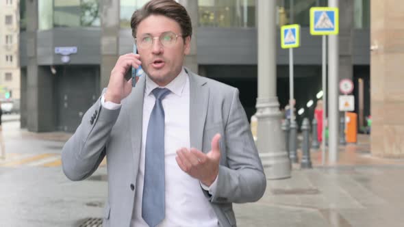 Businessman Talking on Phone Angrily while Walking on Street