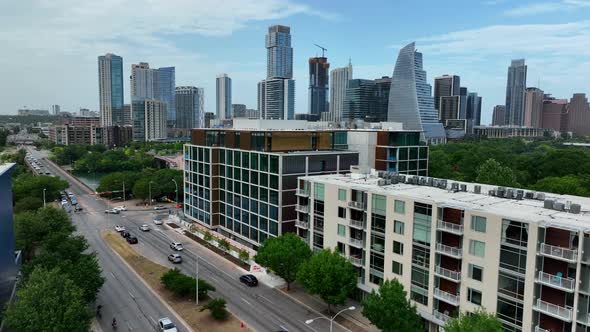 Aerial rising shot reveals Colorado River and Austin, Texas skyline. Cars drive across bridges in ur