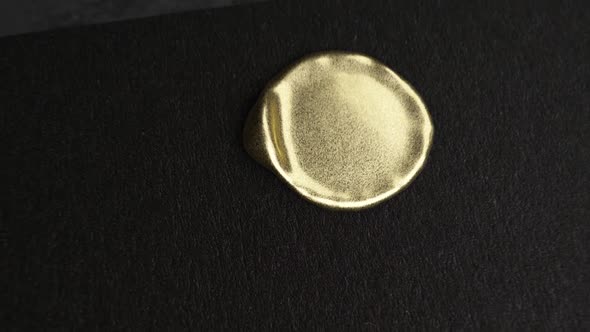 Golden Wax Drop To Black Paper and Golden Stamp Make a Seal