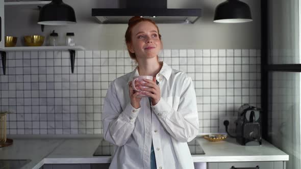Portrait of Redhead Satisfied Woman Wearing Casual Clothes Drinking Coffee on Kitchen Slow Motion