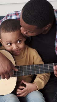 AfricanAmerican Man Teaching His Little Son to Play Guitar at Home