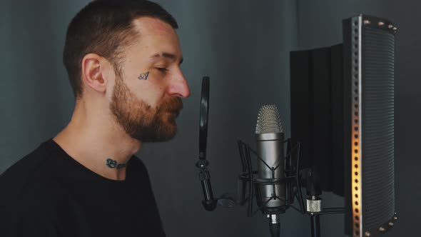 Young Bearded Male Artist Standing Next to Microphone Looking to the Camera Medium Closeup