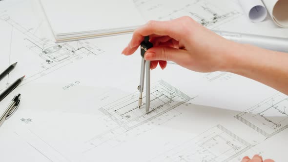 Architect Designer Using Compass to Draw Plan Blueprint Closeup