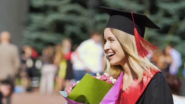 Happy Beautiful Graduating Student Holding Bunch of Flowers, Smiling to Camera