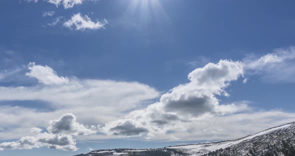 Time Lapse of Cloudscape Behind of the Mountains Top. Snow, Rocks, Cliffs and Deep Blue Sky. High