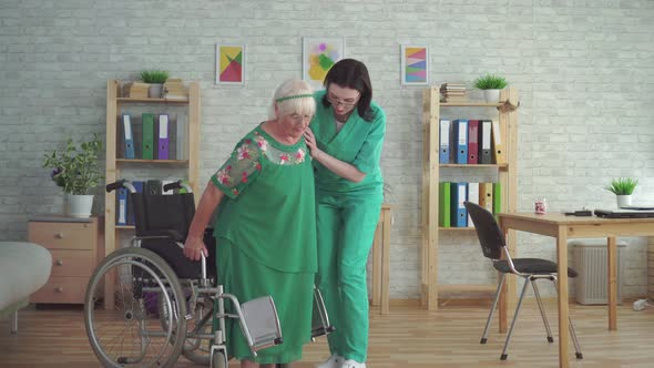 Nurse Helps an Elderly Woman Get Out of a Wheelchair