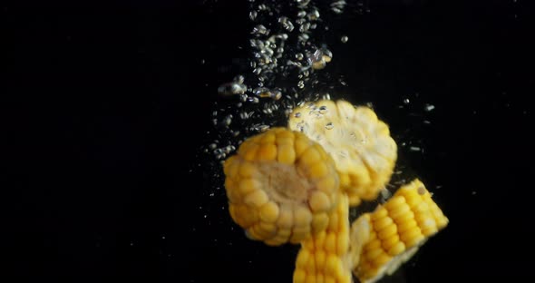 Pieces of Corn Fall Into the Water with Air Bubbles. 