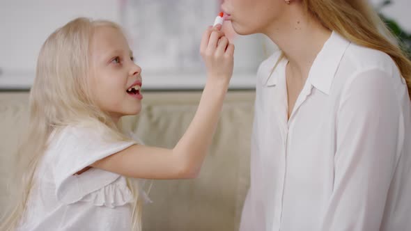 Blond Little Girl Putting Lipstick on her Mom