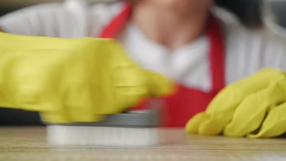 Young Housewife in Yellow Rubber Gloves Scrubs a Stain on the Countertop with Effort