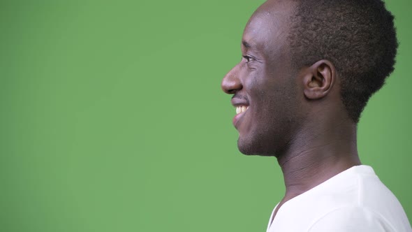 Profile View of Young Happy African Man Against Green Background