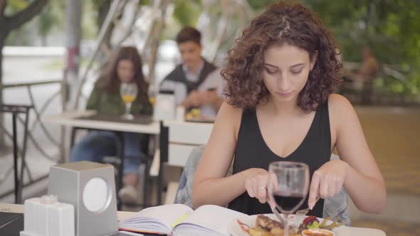 Young Beautiful Curly Woman Eating Tasty Meat Food at Street Cafe