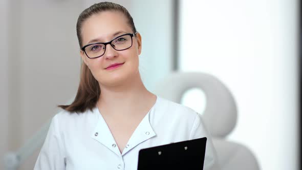 Medium Closeup Portrait of Smiling Young Medical Woman Wearing Glasses Posing and Looking at Camera