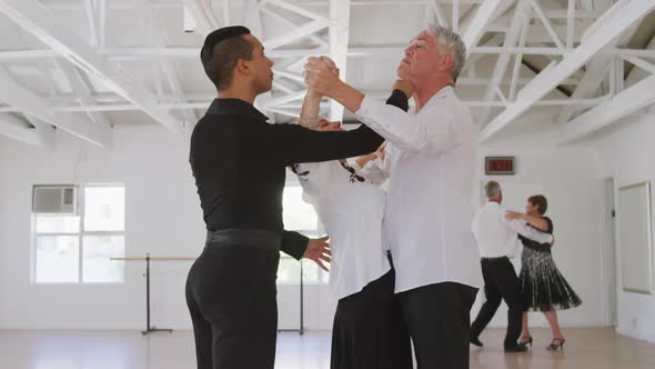 mixed race male dance teacher taking a ballroom dancing class at a dance studio