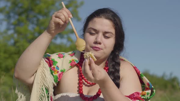 Portrait of Beautiful Overweight Woman Eating Pancakes with Honey Outdoors