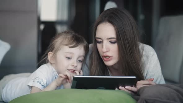 Cute Little Small Kid Child Daughter With Adult Mum Using Digital Tablet Technology Device 