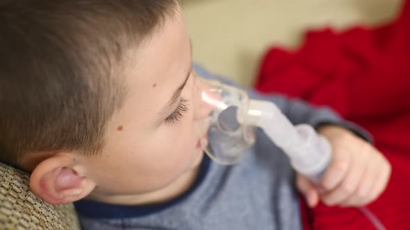 Child Teenager Boy Breathes Through an Inhaler or Nebulizer