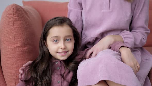 Mom and Daughter in Purple Dresses Sitting on Couch at Home on Christmas Day