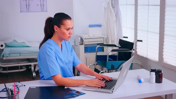 Woman Medical Practitioner Typing Patient Health Report on Laptop