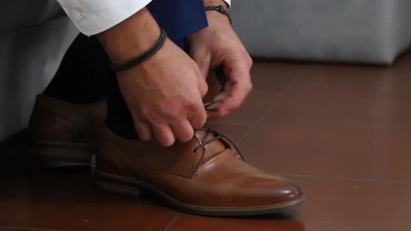 Man Ties Up Shoelaces on Brown Leather Shoes