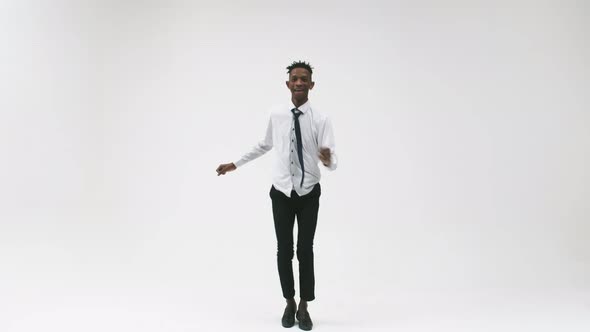 Emotional Confident Black Man in White Shirt and Tie Dances and Jumps High on White Background in