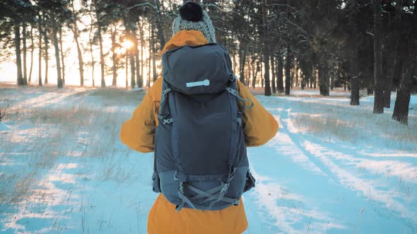 A Young Caucasian Girl with Backpack Going on Winter Forest Road in Snow Covered Winter Pine Forest