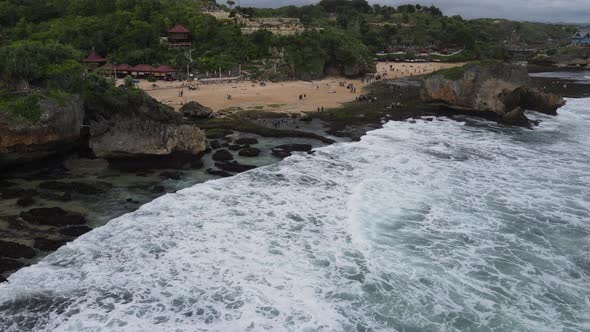 Aerial view of tropical beach in Gunung kidul, Indonesia with green and rocky cliff.