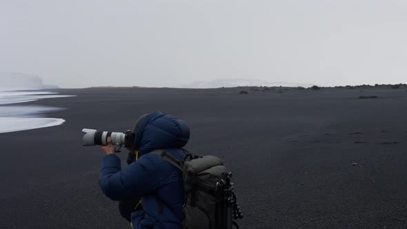 Photographer Holding Camera To Photograph From Black Sand Beach