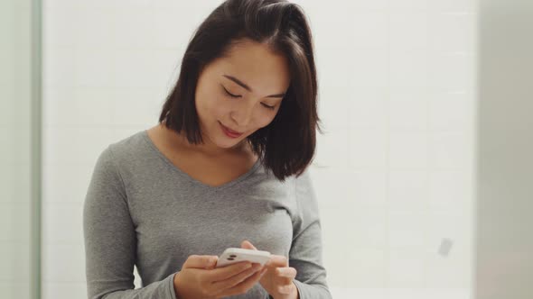 Pretty Asian woman texting by phone