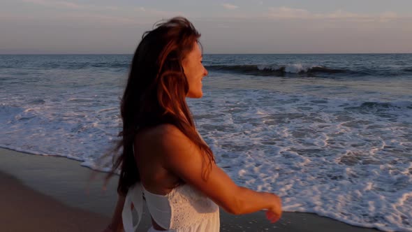 Beautiful woman in a white dress at the beach at sunset