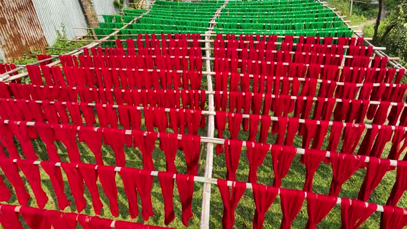 Aerial view of a person hanging to dry red cloths in Dhaka, Bangladesh.