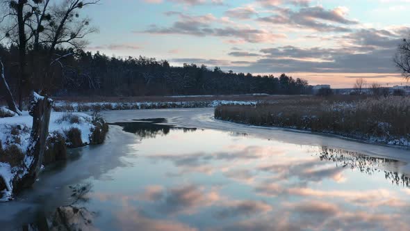 Beautiful winter landscape with winding river and dramatic cloudy sky at sunset